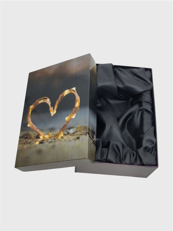 Interior view of luxury gift box with glossy heart-print lid leaning against the base and black satin tray